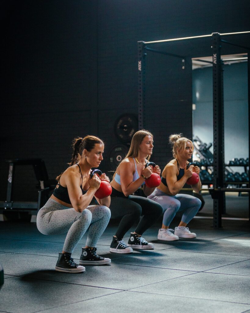3 vrouwen gefocust op hun training met dumbells in de gym van JPT Lifestyle in Groningen